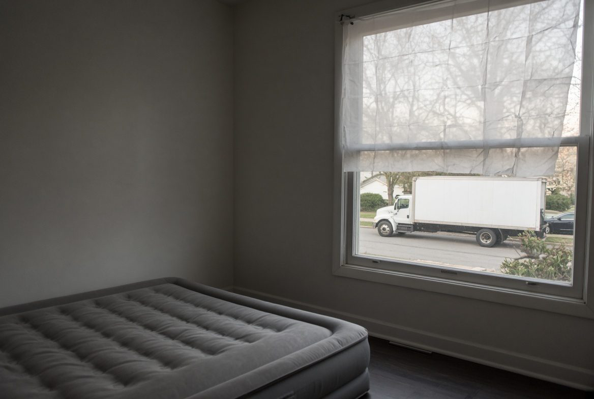 Moving truck outside a window with temporary paper shades, air mattress still up